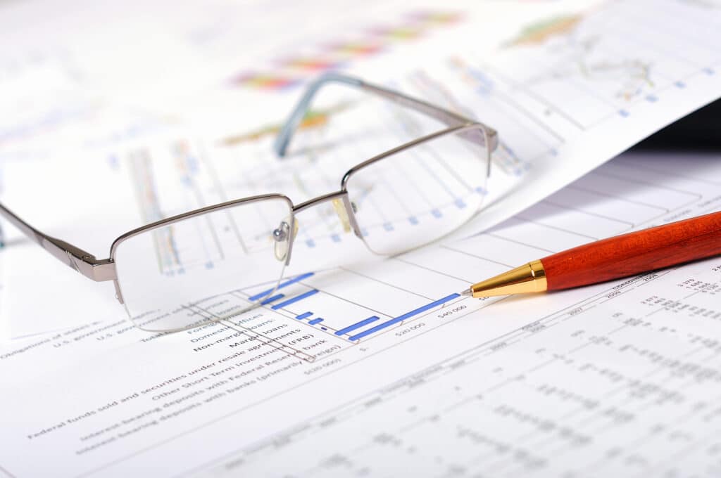 glasses and pen on papers with charts and diagrams - tax accounting services