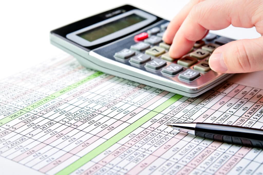 hand on calculator and balance sheet - tax accounting services