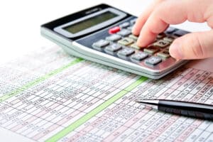 hand on calculator and balance sheet - tax accounting services